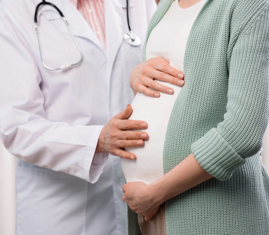 Doctor examining a pregnant woman's belly during checkup.