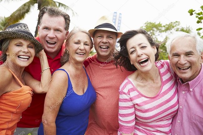 Four friends smiling and enjoying a sunny day outdoors.